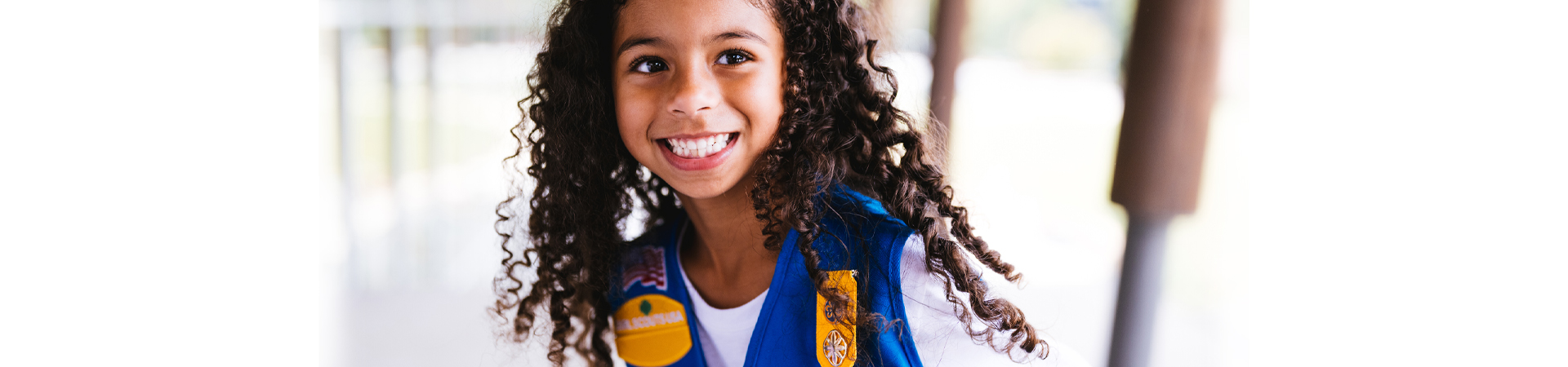  three young girl scouts with their arms wrapped around one another and smiling at the camera 