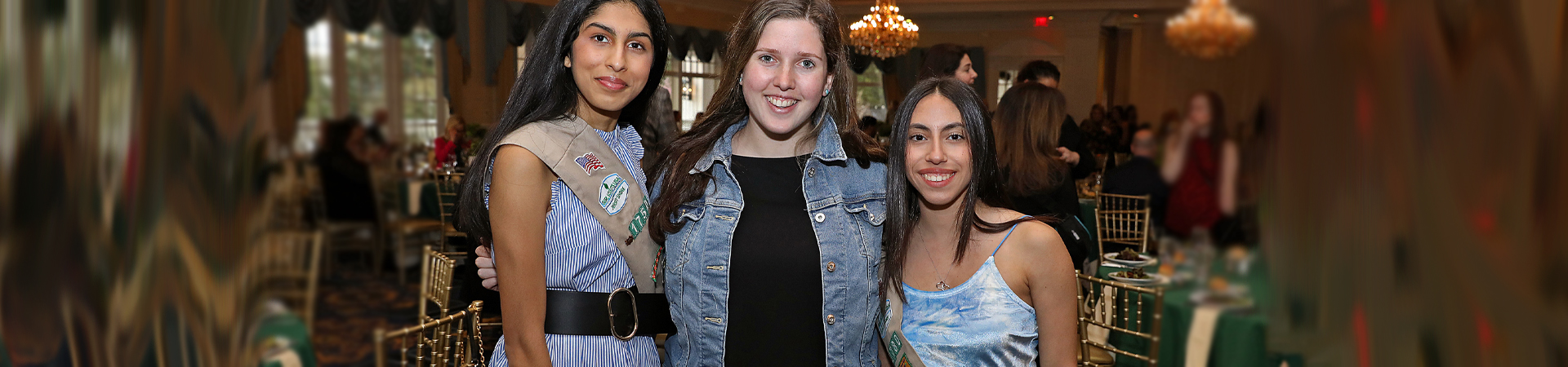  cadette girl scout hosting a table and smiling at a civics event with other middle school and high school girls  